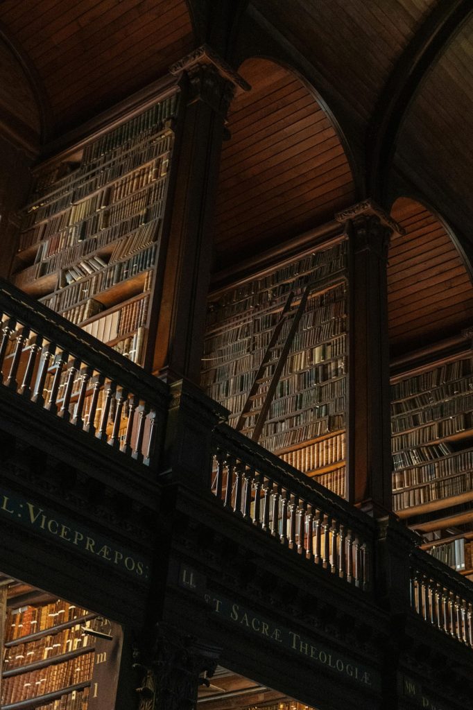 Interior view of the historic Trinity College Library in Dublin, showcasing its ornate wooden shelves filled with books.